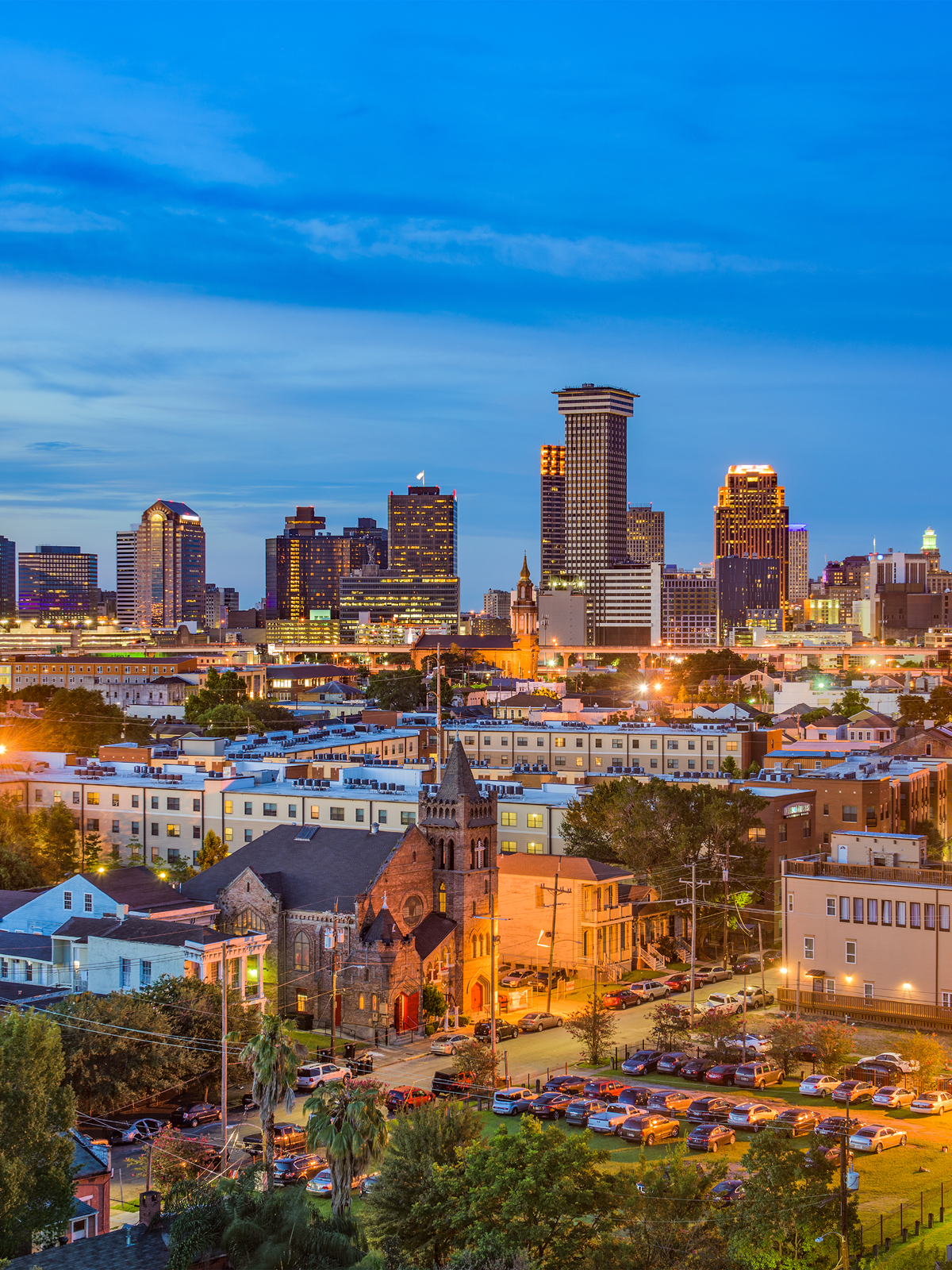 A panoramic view of a city skyline at dusk, showcasing dark buildings outlined by a vibrant sunset